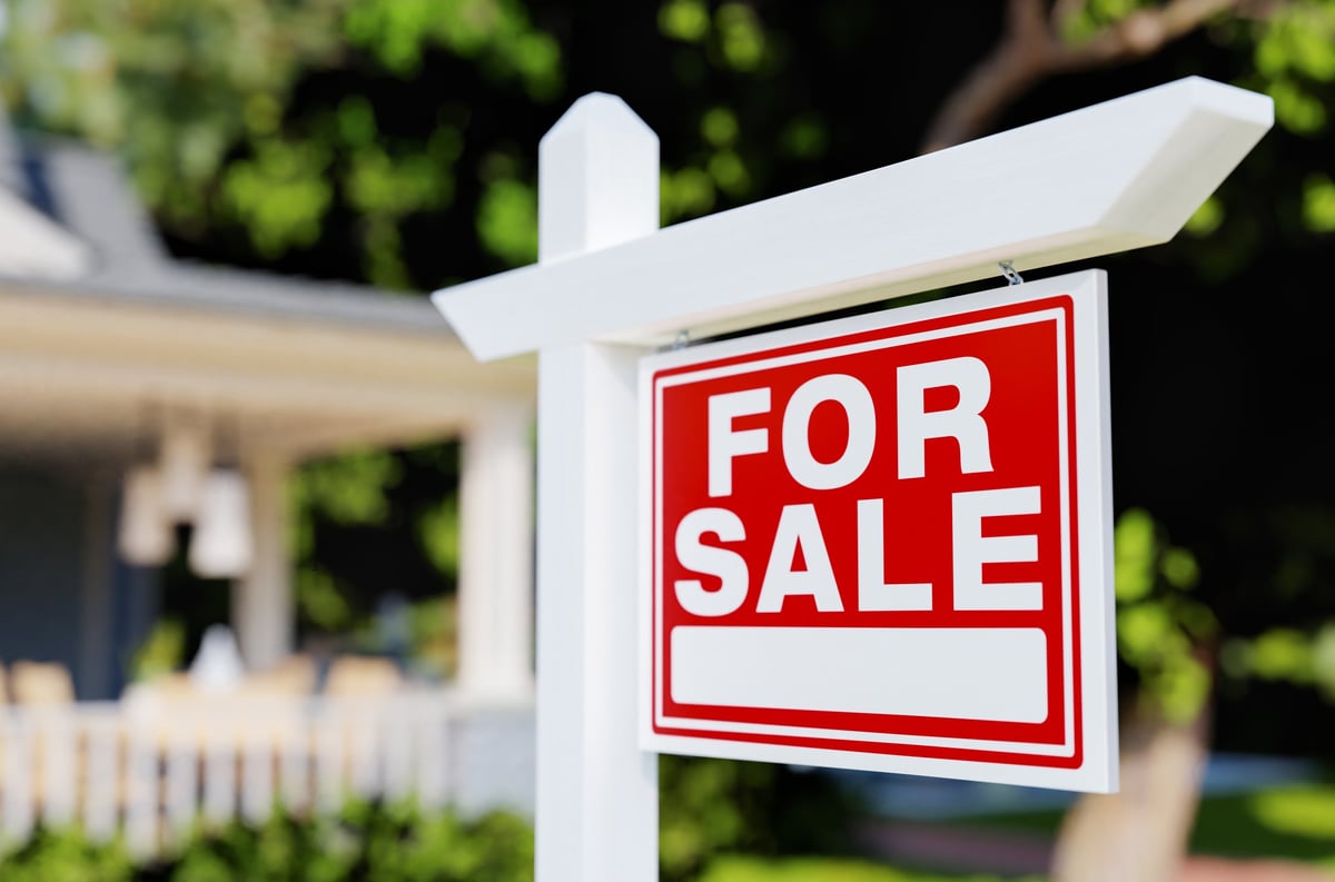 A for sale real estate sign in front of a tidy property